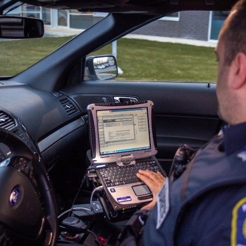 Patrouille mobile de sécurité avec un agent de sécurité dans une voiture de Centurions Solutions regardant son ordinateur de bord